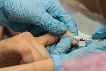 Fototapeta premium The manicurist processes old gel varnish a mill