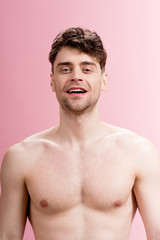 Fototapeta premium handsome, smiling brunette man looking at camera on pink