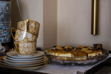 Beautiful golden empty teacups and cake, waiting for dessert to be served