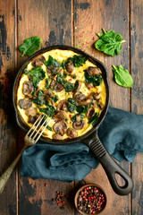 Omelette with mushrooms and spinach in a cast iron pan.Top view with copy space.