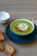 Creamy vegetable soup with kale, cabbage, celery and millet, decorated with olive oil, yoghurt sauce and chilli flakes. Served with toasted bread and lemony yoghurt sauce. Selective focus.