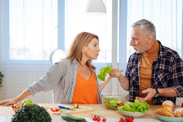 Emotional couple having argument while cooking salad for lunch