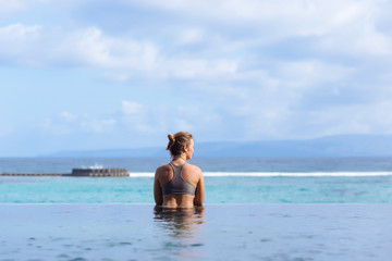 Woman in swimsuit in swimming pool with view of ocean