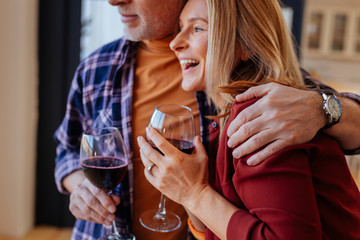 Bearded husband wearing hand watch hugging his laughing wife