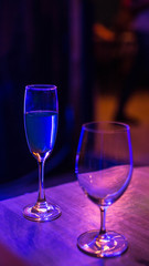 Wine Glasses and Glasses of Champagne over blue spotlights background on table at Night restaurant.