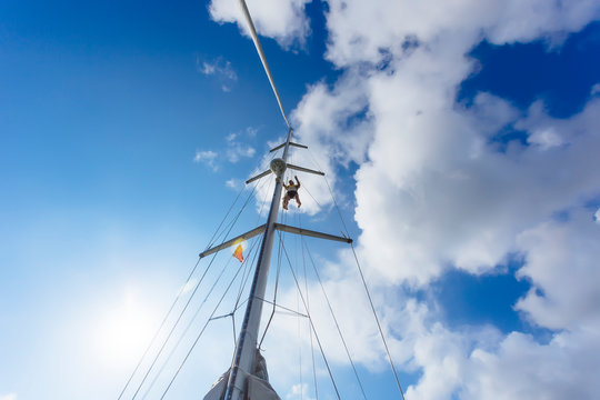Man hanging from mast of sailboat, Lombok, Indonesia