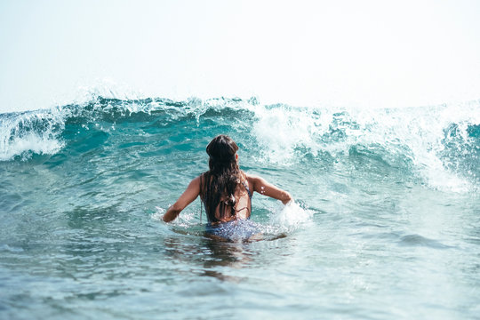 woman in a swimsuit and diving googles playing with the waves on the beach