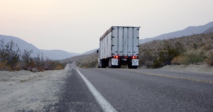 Transport truck drives along empty desert highway