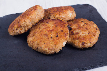 cutlets on a black flat plate, on a white wooden background