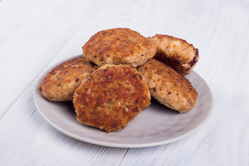 cutlets on a grey plate, on a white wooden background