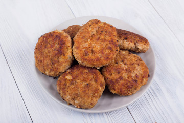 cutlets on a grey plate, on a white wooden background