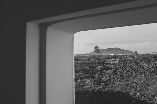 Volcano and palm trees seen through window of Fundation Cesar Manrique, Lanzarote, Canary Islands, Spain