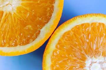 two bright slices of juicy orange on a blue background, macro