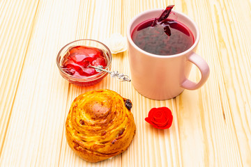 Karkade tea from hibiscus petals (Sudanese rose). Gentle romantic breakfast concept. Buns, meringues, strawberry jelly. On a wooden background.