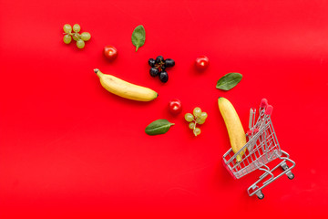 making purchase products online with fruits and mini trolley on office desk background top view copyspace