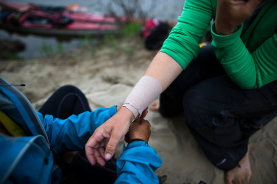 A woman tends to her traveling companions forearm after developing a case of tendonitis from excessive kayaking on the shore of the Amur RIver in far east Russia.