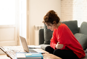 Portrait of a happy young woman working on laptop sitting on the sofa. In work and study concept