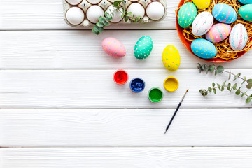 Colorful Easter eggs and paint for celebration on white background top view mock up