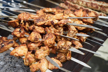 Roasted chicken wings kebab on skewers, close-up, outdoors. 