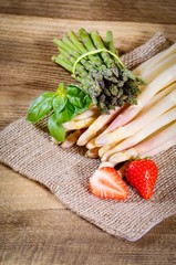 Weisser und grüner Spargel dekorativ auf einen Holztisch angerichtet