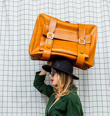 woman in hat and green cloak in 90s style with travel suitcase