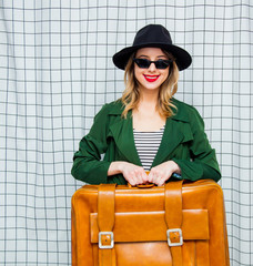 woman in hat and green cloak in 90s style with travel suitcase