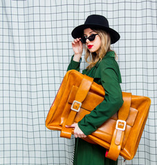 woman in hat and green cloak in 90s style with travel suitcase