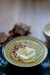 Creamy vegetable soup with kale, cabbage, celery and millet, decorated with olive oil, yoghurt sauce and chilli flakes. Served with seed crackers and lemony yoghurt sauce. Selective focus.