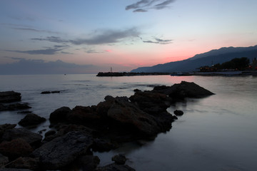 Pink and blue sunset on the beach in Creta, Greece. Beach with blacks rocks and waves at dusk