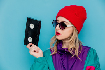woman in red hat, sunglasses and suit of 90s with VHS cassette