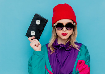 woman in red hat, sunglasses and suit of 90s with VHS cassette