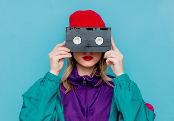 woman in red hat, sunglasses and suit of 90s with VHS cassette