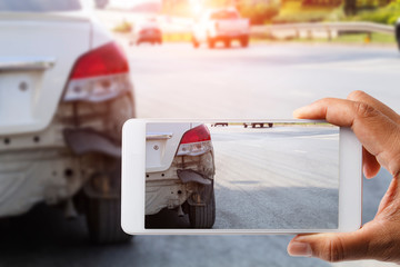 Car insurance agents take pictures of accident-damaged vehicles with a smartphone as a proof of insurance claim