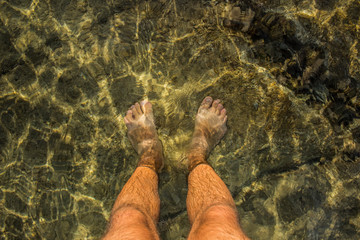 unfocused fuzzy male feet stay in blurred and glares water