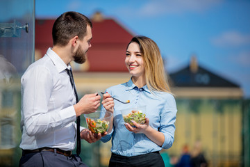 young businesswoman and businessman eating together salad