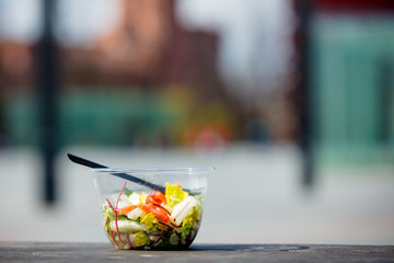 lunch salad with fork in plastic box on wooden banch