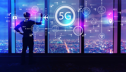 5G network with man writing on large windows high above a sprawling city at night