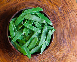 Wooden bowl filled with fresh snow peas