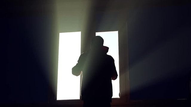 Close up silhouette man stand lifts his hands up near window in dark sunshine jalousie installing apartment interior inside sunlight view closeup flat slow motion