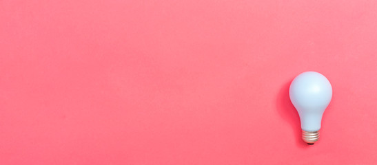 Colored light bulb on a pink paper background