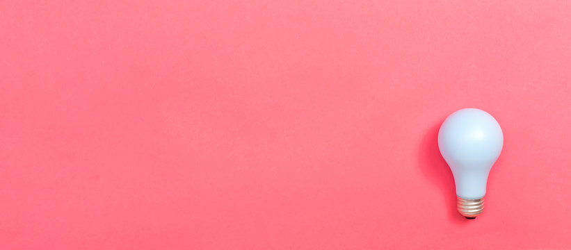 Colored light bulb on a pink paper background