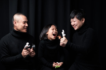 Asian couples and children, shooting indoors, holding small dolls and playing fun.