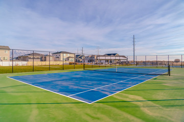 Tennis court against homes mountain and sky