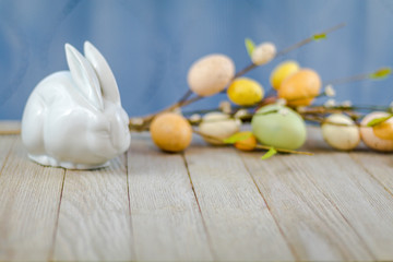 Spring Easter background on wooden board with white ceramic rabbit and colorful tulips and eggs room for text