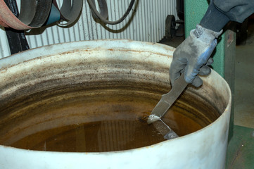 The professional knife maker dips the blade into the gunk bucket of water to cool it off during the grinding process in the workshop in Missouri.