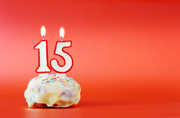 Fifteen years birthday. Cupcake with white burning candle in the form of number 15. Vivid red...