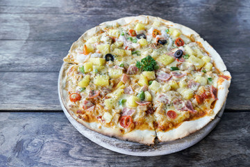 Homemade hawaiian Pizza, pineapple, ham and cheese on wooden table. top view