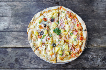 Homemade hawaiian Pizza, pineapple, ham and cheese on wooden table. top view