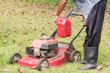 Men are adding oil to the lawn mower.