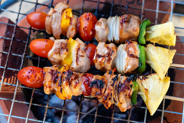 Skewers with pieces of grilled barbecue, green bell pepper, red tomato and meat for sell in street market, Thailand, closeup